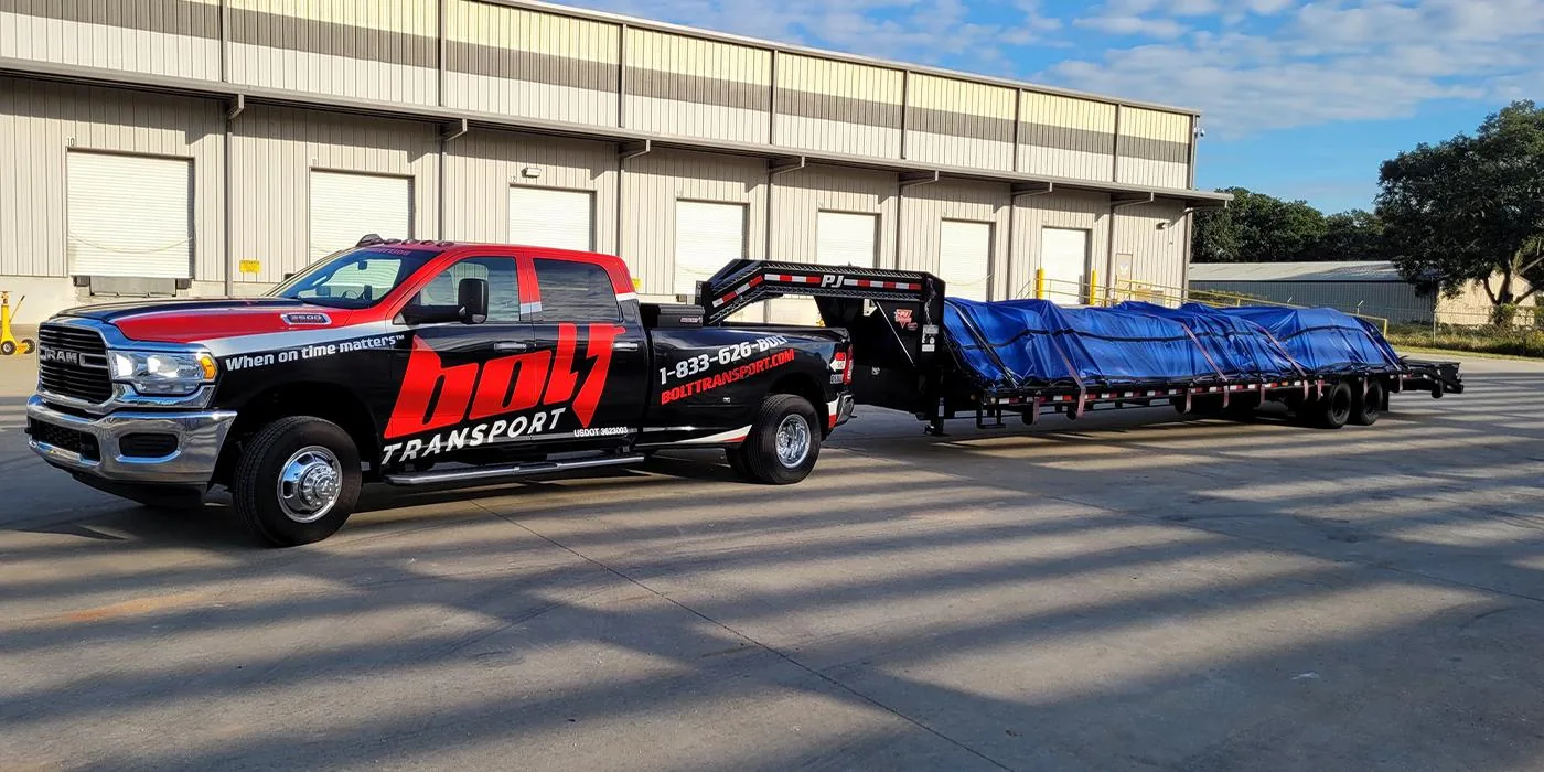Hotshot owner operator hauling industrial equipment on a flatbed trailer